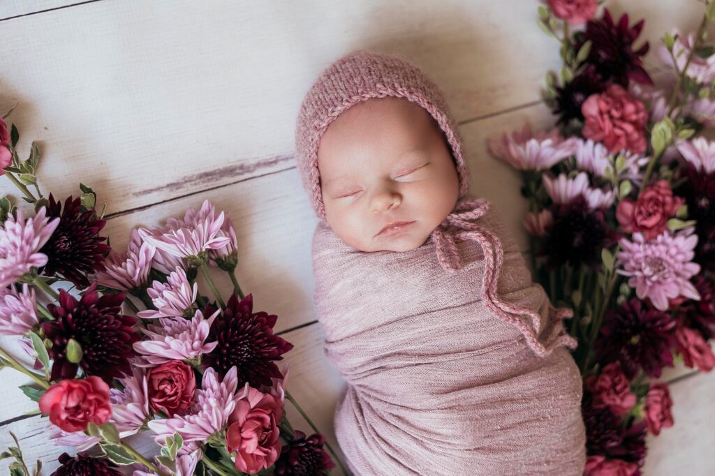 Newborn wrapped in dusty rose swaddle with flowers – floral setup for Sacramento newborn session